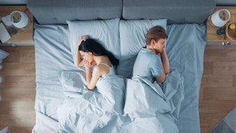 Ein Paar ein Mann und eine Frau liegen mit dem Rücken zueinander im gemeinsamen Bett