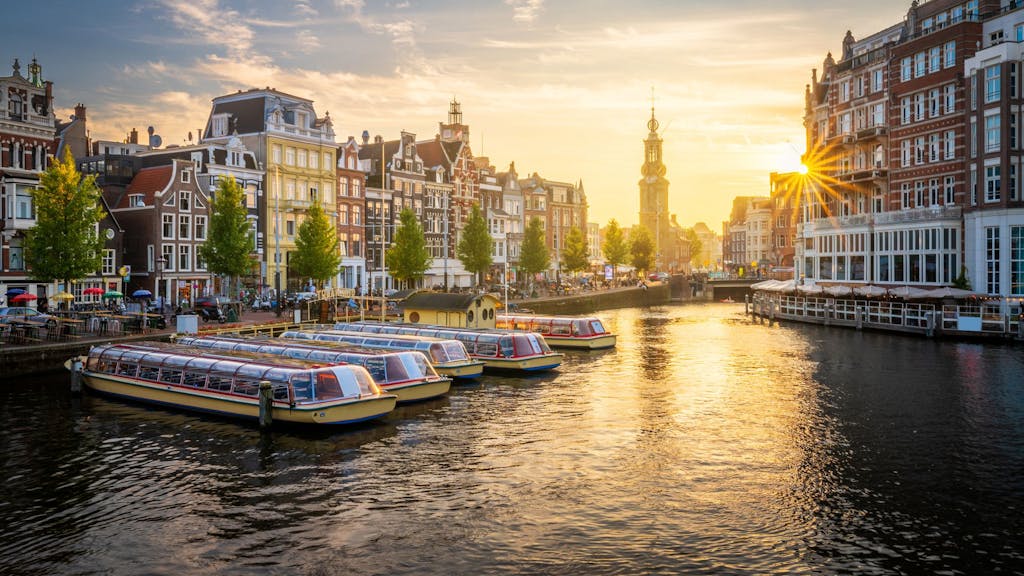 Auf dem Foto sieht man Amsterdam und einen seiner Kanäle im Sonnenuntergang.