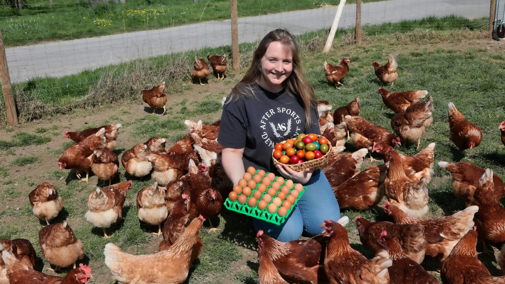 Marit Wirtz mit einem Korb und einer Palette Eiern zwischen Dutzenden Hühnern.