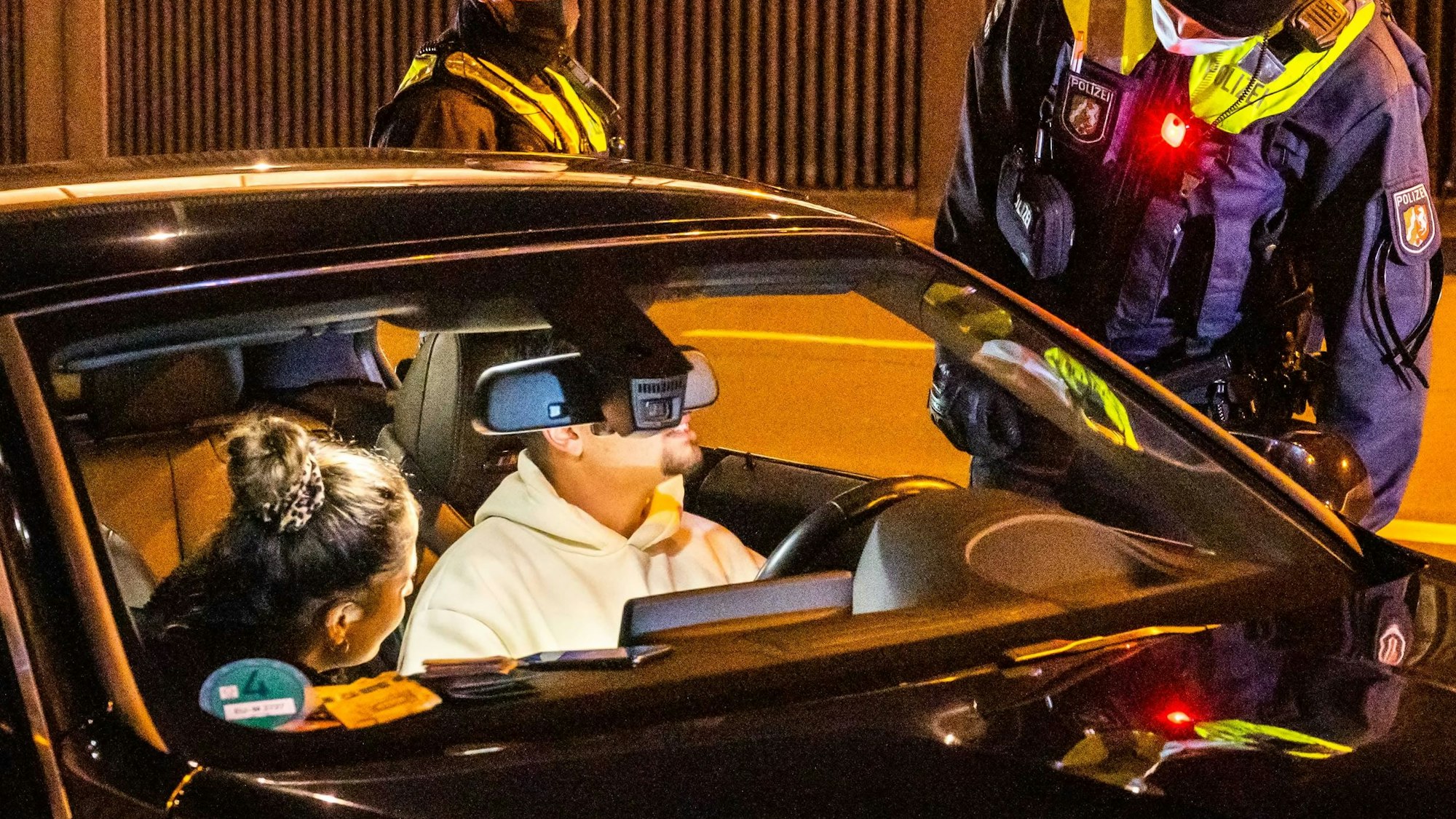 Polizeibeamte, die einen männlichen Fahrer und seine weibliche Mitfahrerin in einem schwarzen Wagen in einem Tunnel kontrollieren
