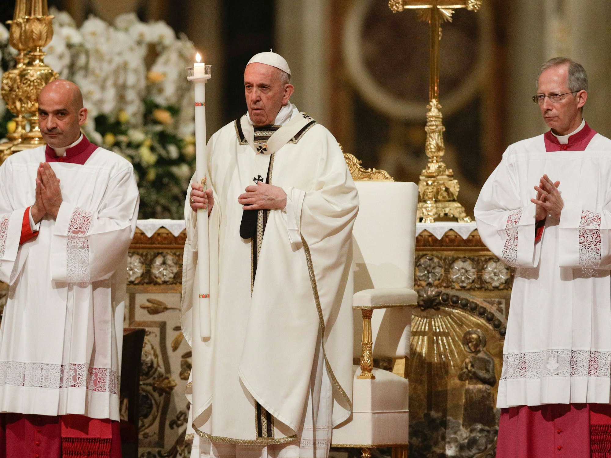Papst Franziskus hält eine Kerze, während er der feierlichen Osternacht im Petersdom vorsitzt. Er trägt ein weißes Gewand.
