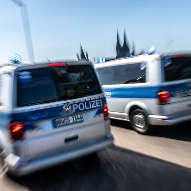 Zwei Polizeifahrzeuge sind mit Blaulicht auf der Deutzer Brücke im Einsatz. Im Hintergrund sind die zwei Türme des Kölner Doms (Symbolbild)