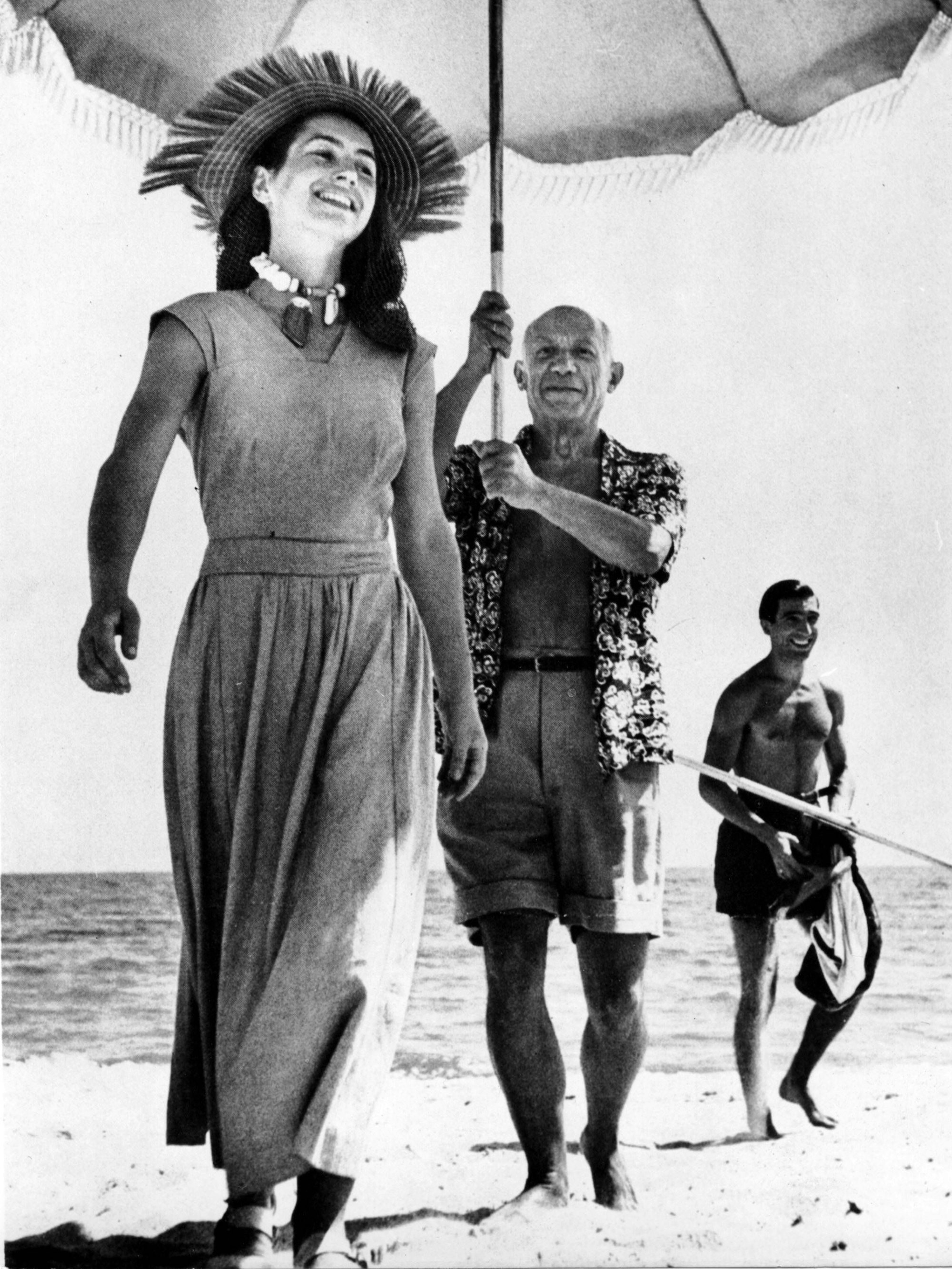 Pablo Picasso hält einen Sonnenschirm über den Kopf der lachenden Francoise Gilot.