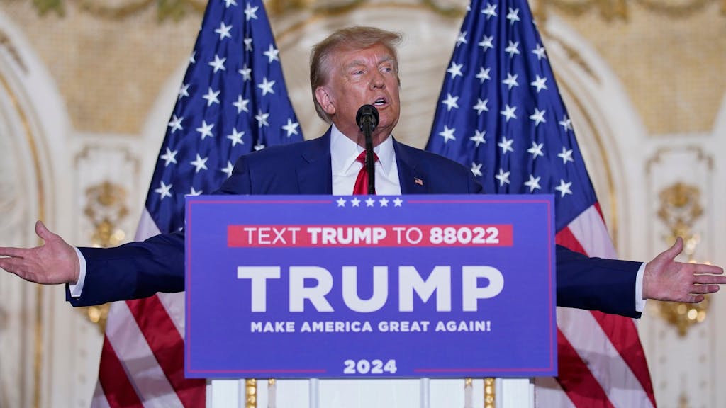 Auf dem Bild zu sehen, wie Donald Trump auf einer Bühne steht und spricht. Das Bild wurde in seinem Anwesen Mar-a-Lago in Florida aufgenommen.