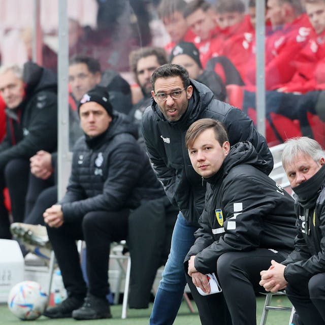 Boris Schommers steht mit anderen Vereinskollegen als Trainer am Spielfeldrand eines Fußballfeldes und verzieht konzentriert das Gesicht.&nbsp;