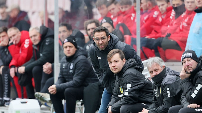 Boris Schommers steht mit anderen Vereinskollegen als Trainer am Spielfeldrand eines Fußballfeldes und verzieht konzentriert das Gesicht.&nbsp;