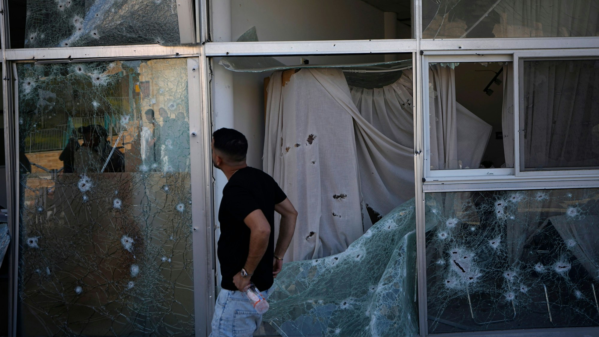 Ein Mann in Shlomi (Nordisrael) schaut sich die Schäden an einem Geschäft an, die durch abgefangenes Raketenfeuer entstanden sind.