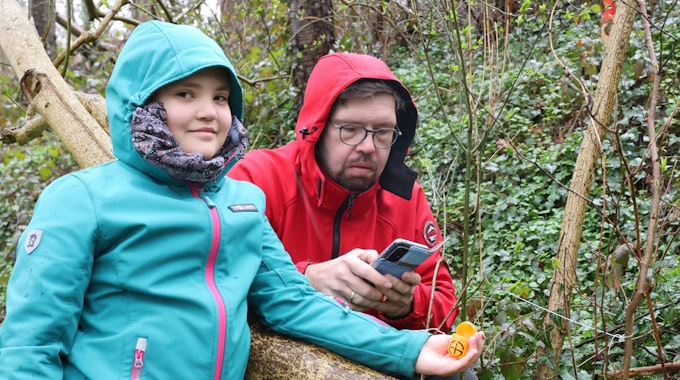 Zu sehen sind ein zehnjähriges Mädchen mit ihrem Vater in der Natur bei der Ostereiersuche. Es regnet.&nbsp;
