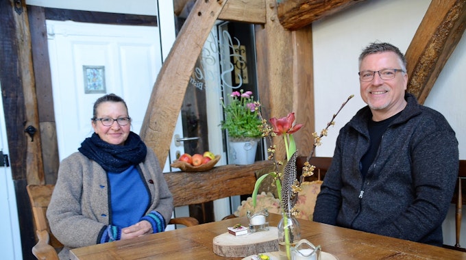 Eine Frau und ein Mann sitzen an einem Holztisch eines Cafés. Im Hintergrund sind Holzbalken zu sehen.&nbsp;