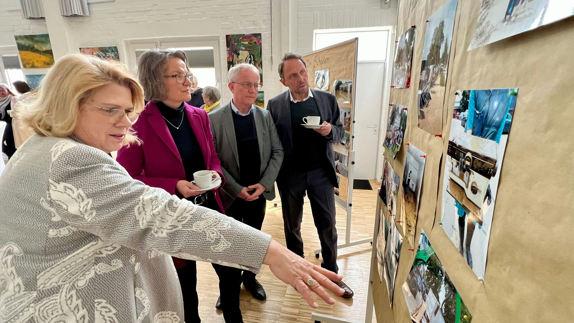 Petra Jennen (Awo) zeigt Heimatministerin Ina Scharrenbach, MdL Rüdiger Scholz und OB Uwe Richrath Aufnahmen von den Aufräumarbeiten nach der Wupperflut im Juli 2021