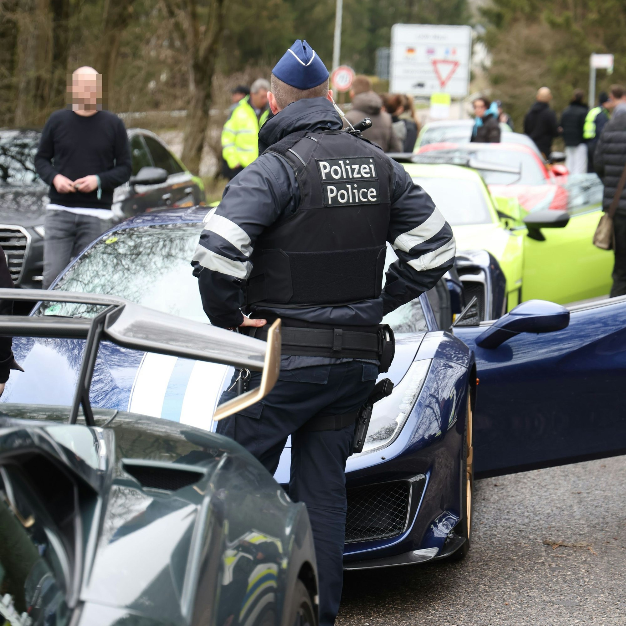 Der belgische Polizeibeamte begutachtet die Reihe wartender Sportwagen.