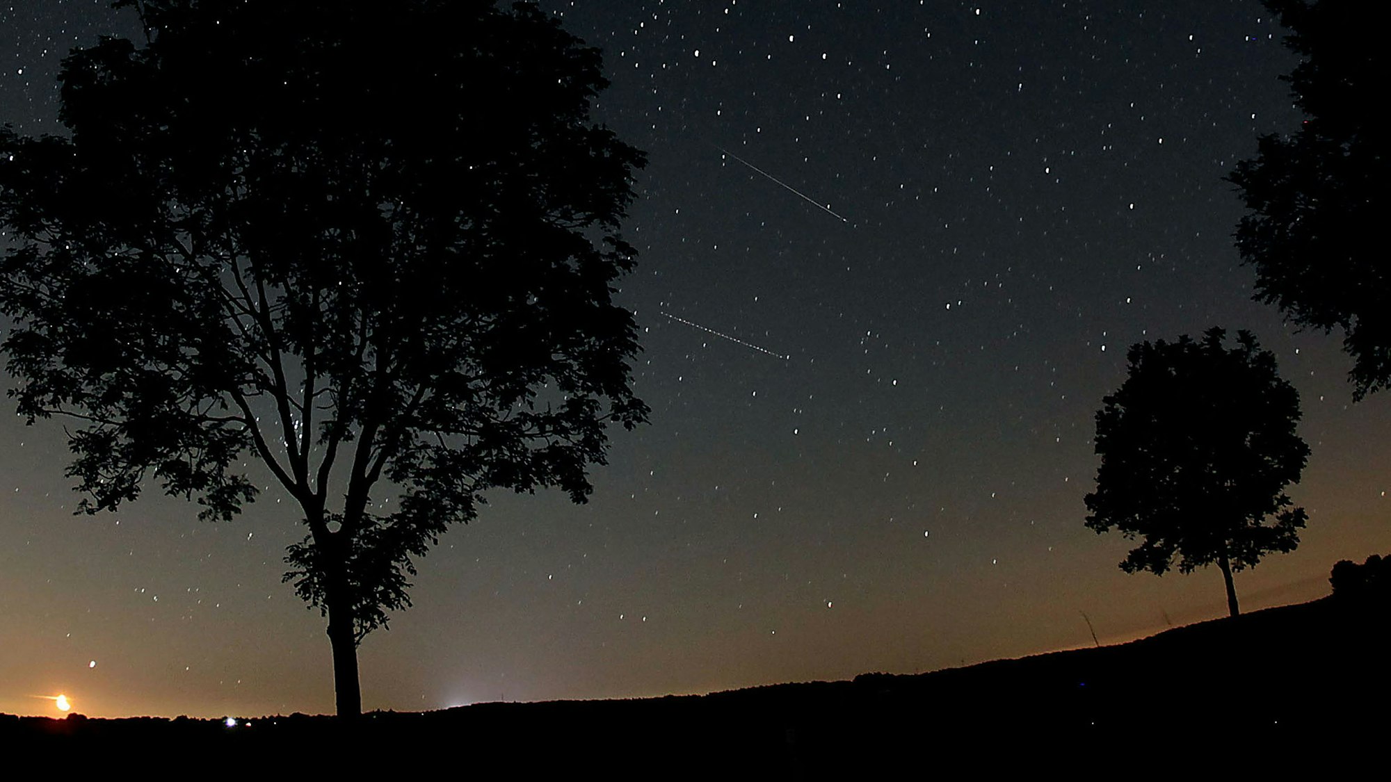 Sternschnuppen der Perseiden (Bildmitte) sind in der Nähe von Nettersheim in der Eifel am Nachthimmel zu sehen.