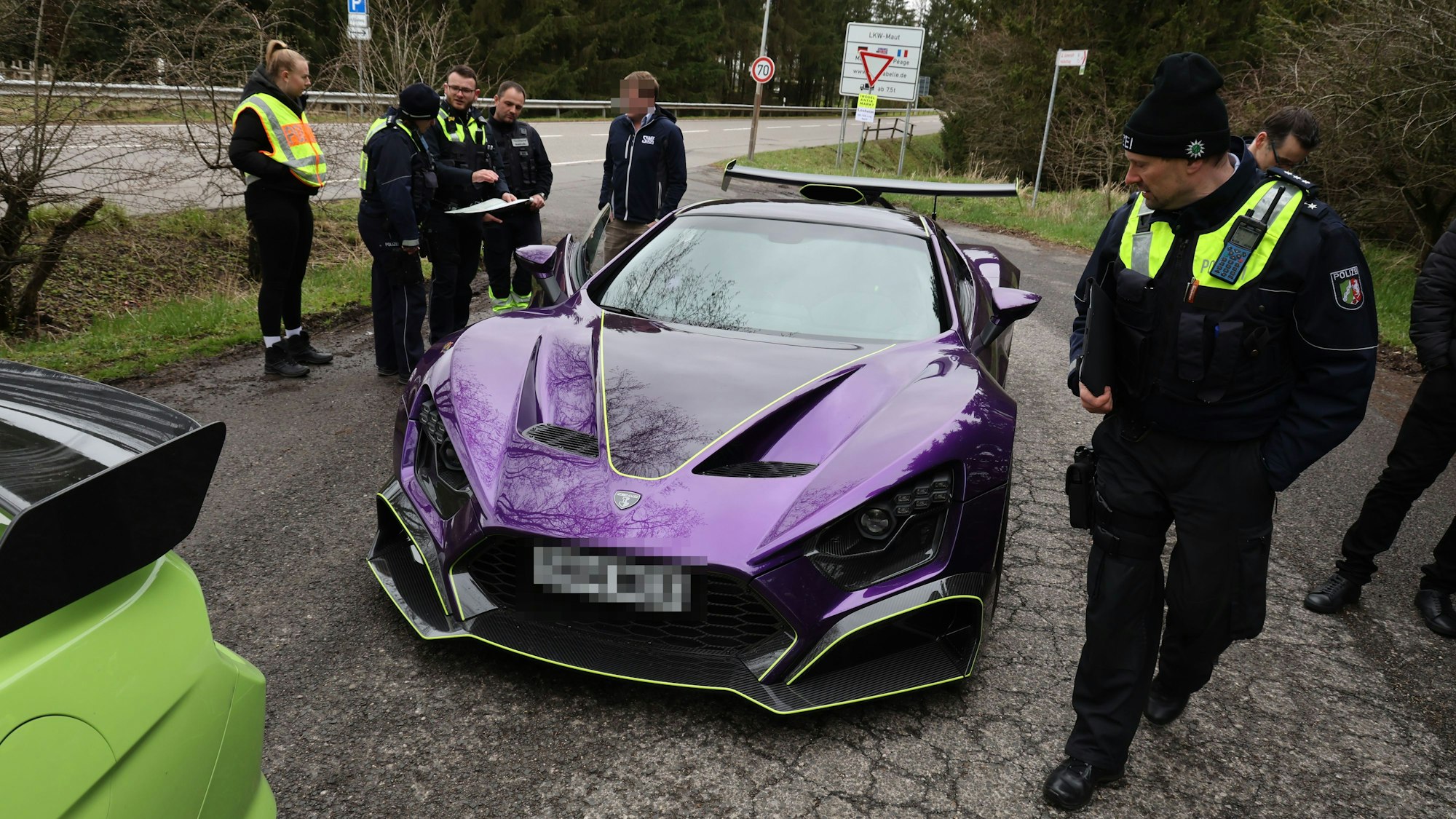 Polizisten beäugen den violett lackierten Supersportwagen.