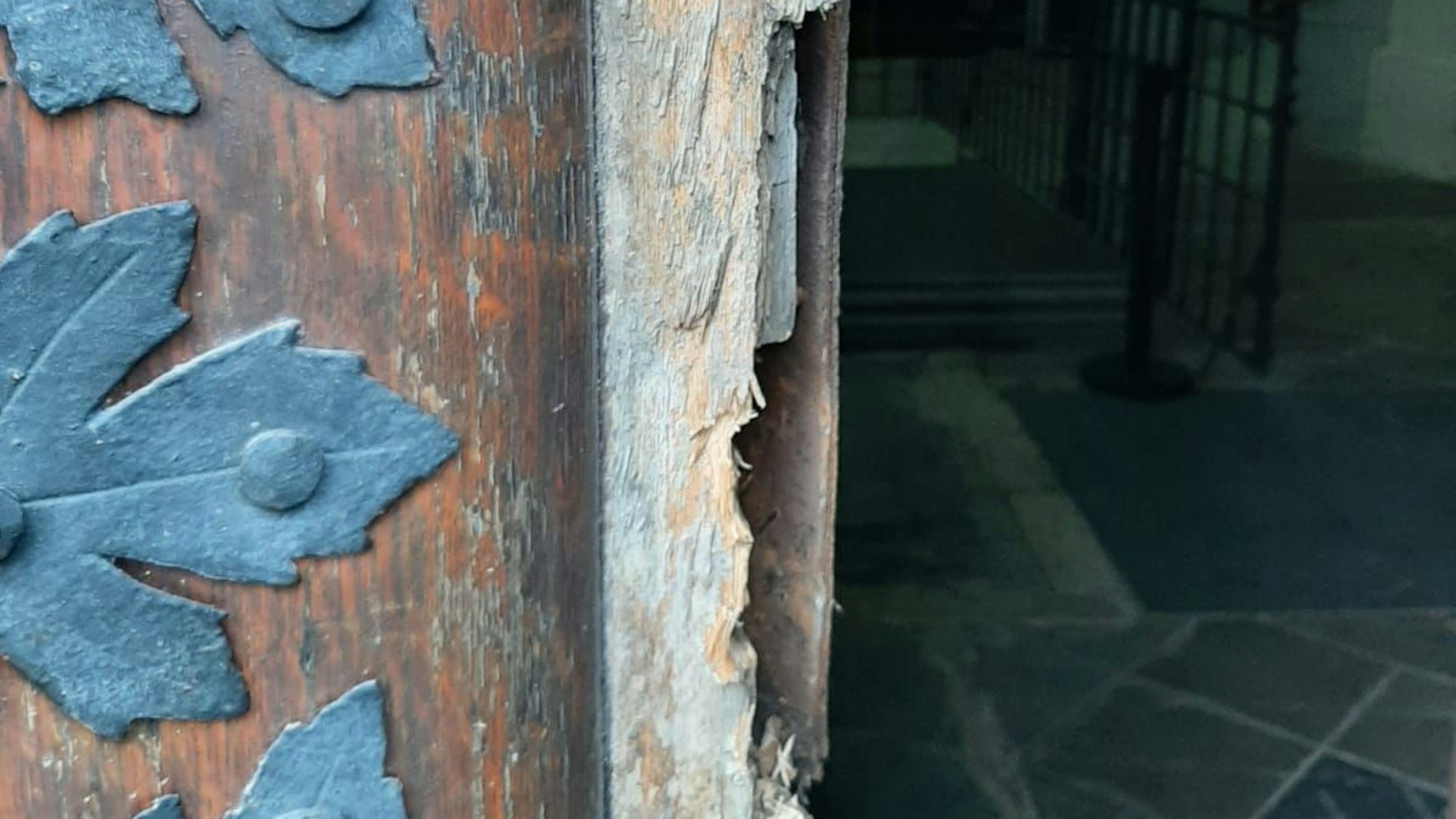 Eine Tür mit Eisenbeschlägen ist an der Stelle, wo sonst das Schloss sitzt, aufgebrochen.