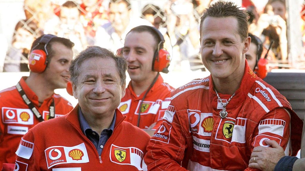 Michael Schumacher und Jean Todt lächeln gemeinsam im Fahrerlager der Formel 1.