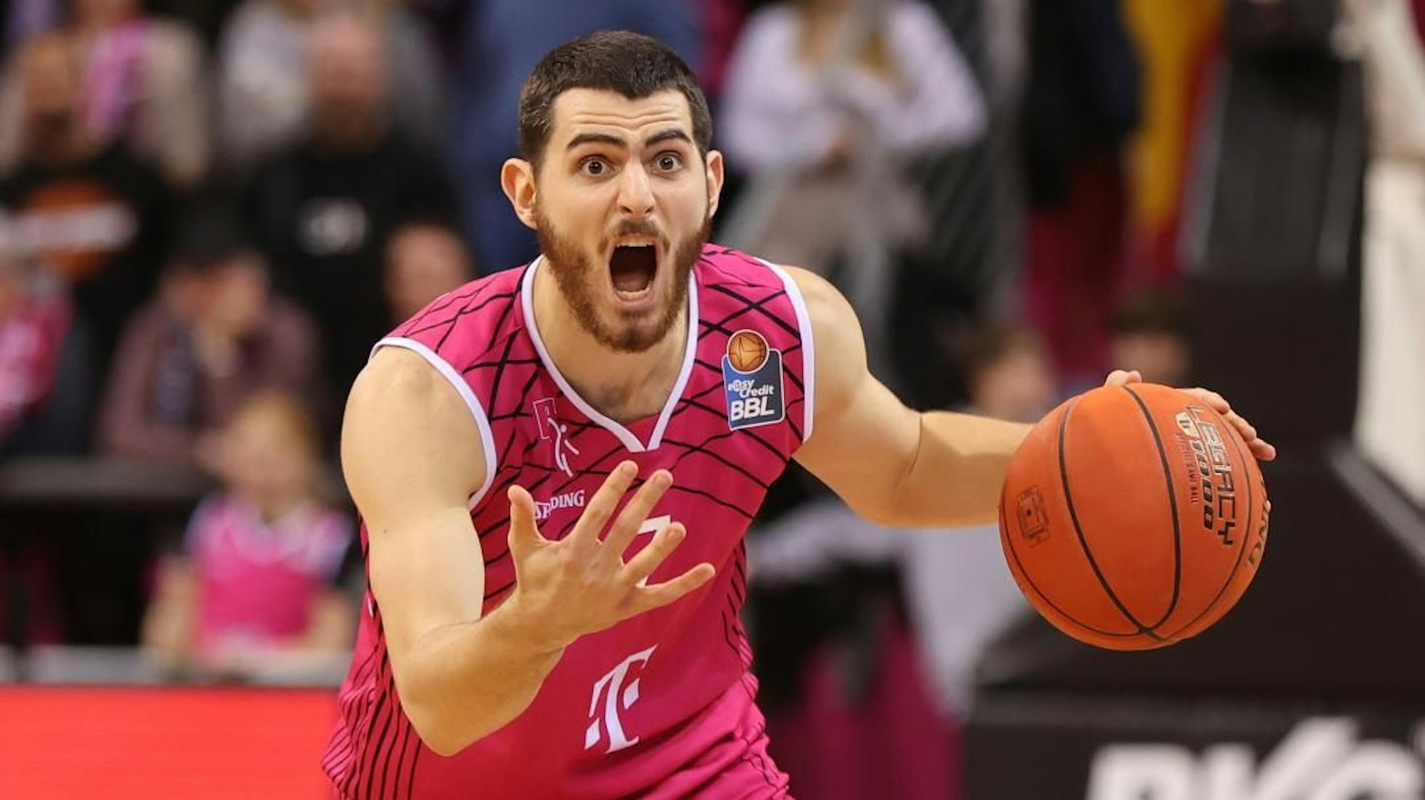 Sebastian Herrera im Telekom Baskets Laibchen schreit, mit Basketball in der Hand