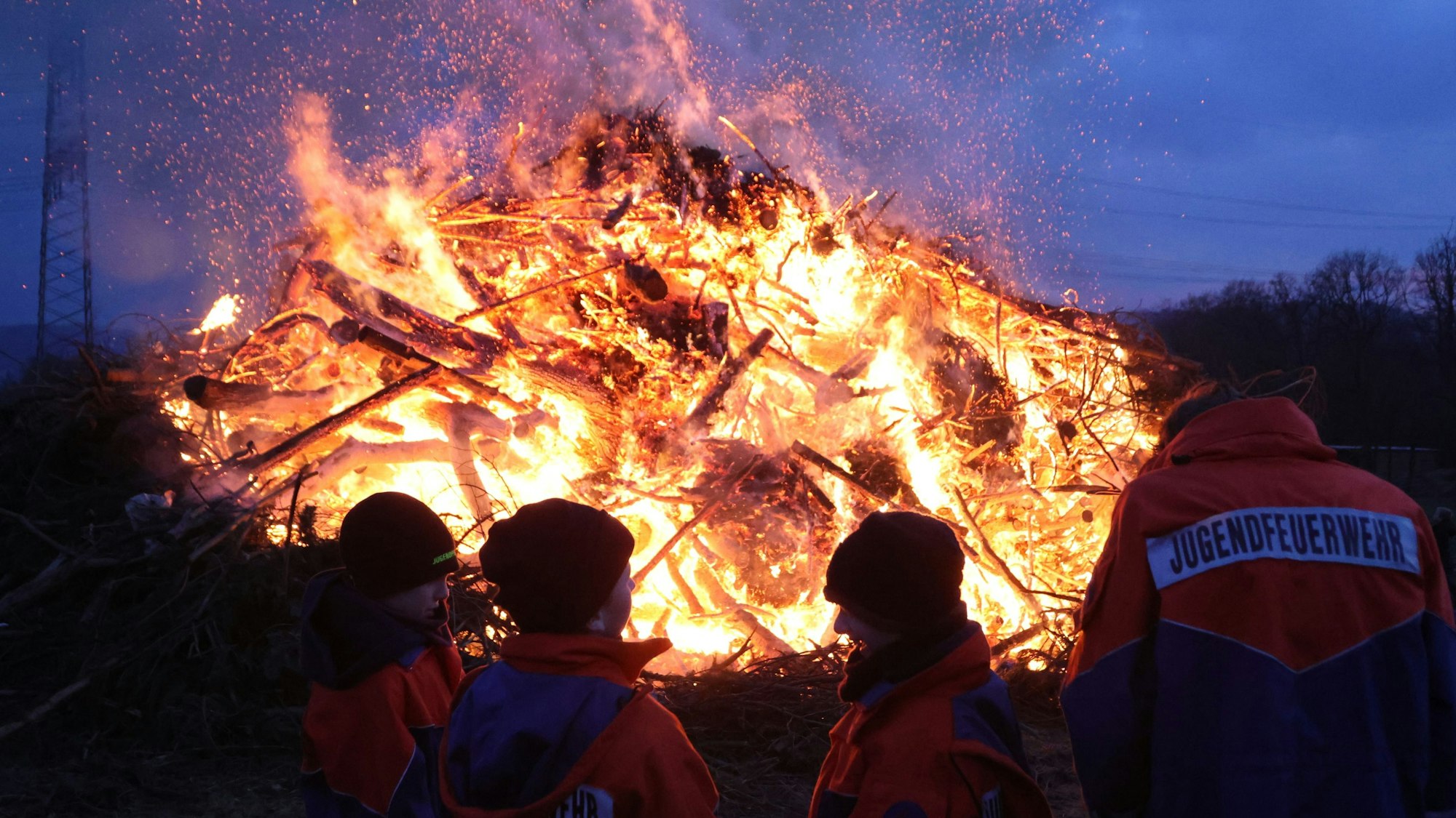 Das Osterfeuer in Heischeid brennt in der Abenddämmerung.