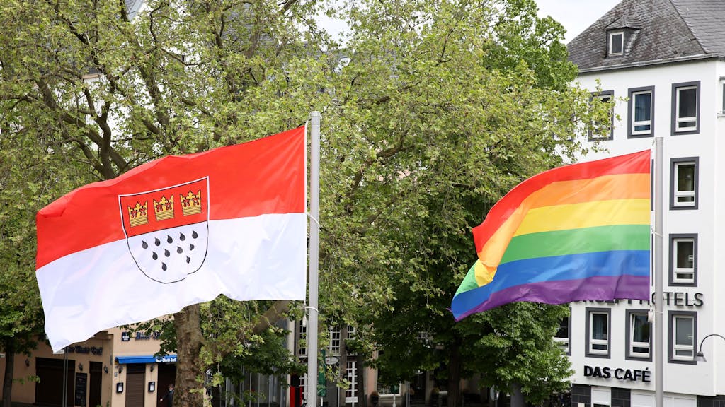 Die Köln-Fahne und die Regenbogenflagge im Wind vor dem Rathaus.