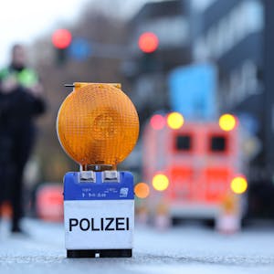 Polizei-Warnbake auf Aachener Str. mit Rettungswagen und Beamten im Hintergrund.