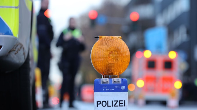 Polizei-Warnbake auf Aachener Str. mit Rettungswagen und Beamten im Hintergrund.