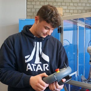 Berufsschüler Liam Allen führt die neue Robotik-Anlage am Thomas Esser Berufskolleg vor.