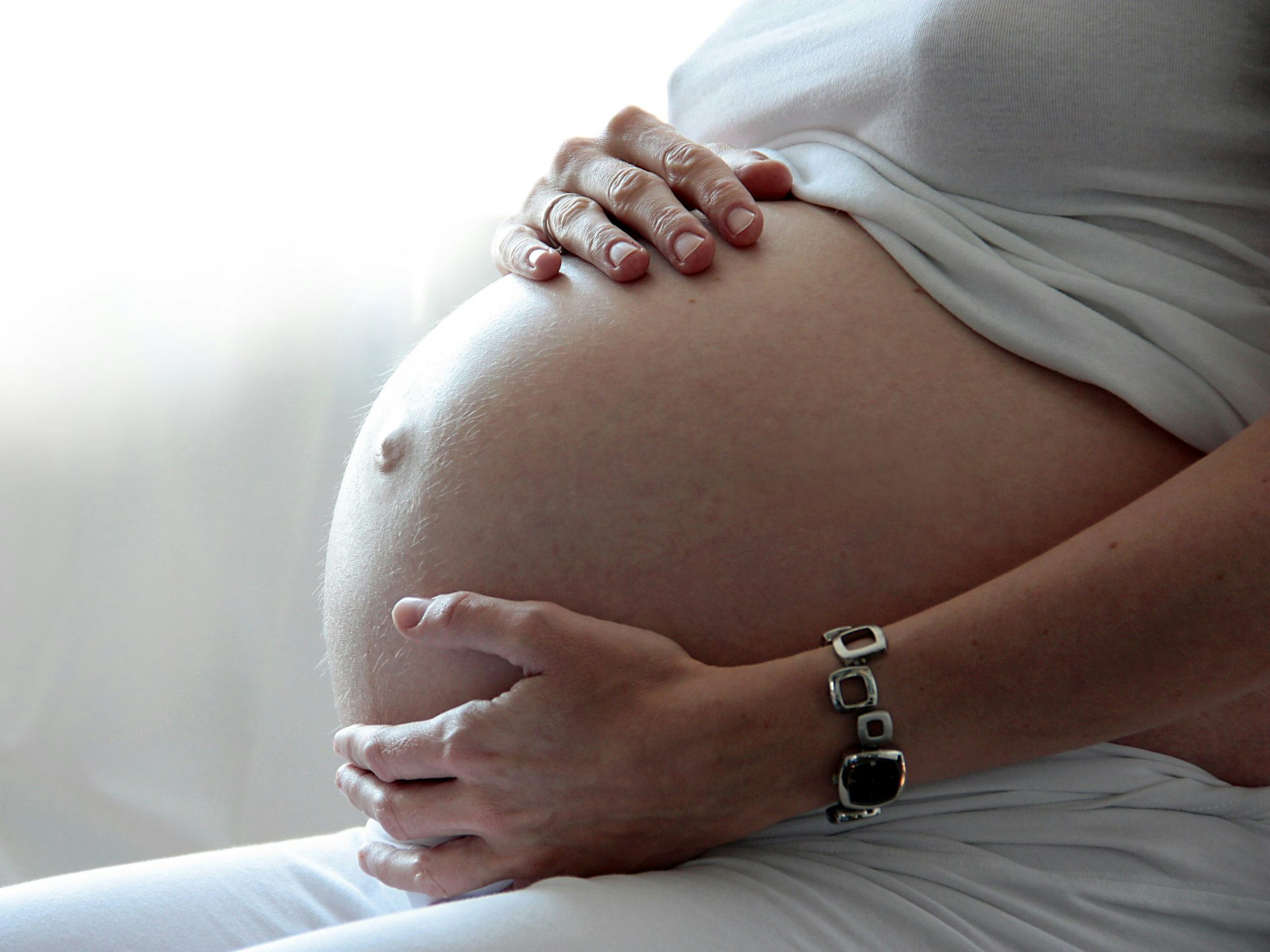 Eine Frau hält ihren schwangeren Bauch.