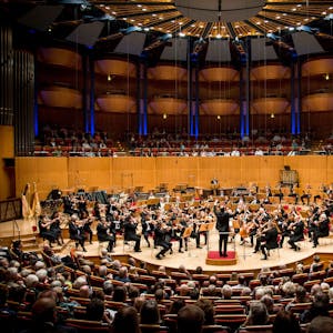Das Gürzenich-Orchester in der Totalen. Das Orchester spielt in der Kölner Philharmonie, der Dirigent hat die Arme erhoben.&nbsp;