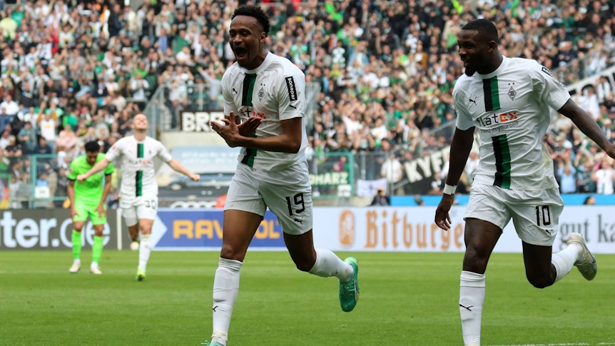 Nathan Ngoumou (l.) bejubelt seinen ersten Bundesliga-Treffer mit Marcus Thuram im Spiel von Borussia Mönchengladbach gegen den VfL Wolfsburg am 9. April 2023.