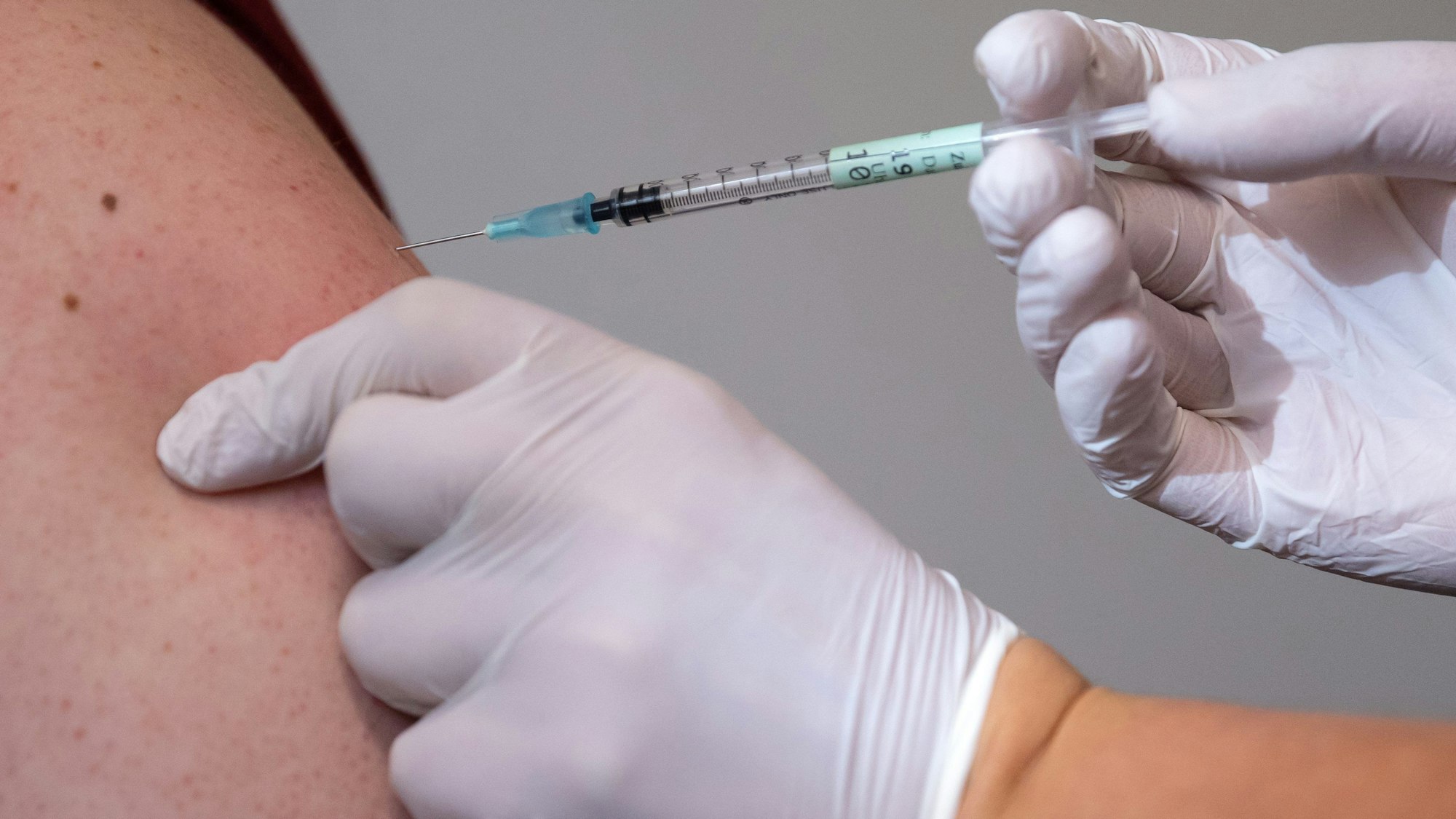 ARCHIV - 19.11.2021, Bayern, Haar: Ein Mann bekommt im Impfzentrum eine Booster-Impfung gegen Covid-19.