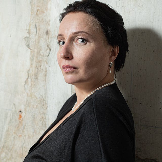 Kateryna Kalytko, eine weiße Fra mittleren Alters mit kurzen dunklen Haaren schaut über ihre Schulter in die Kamera.