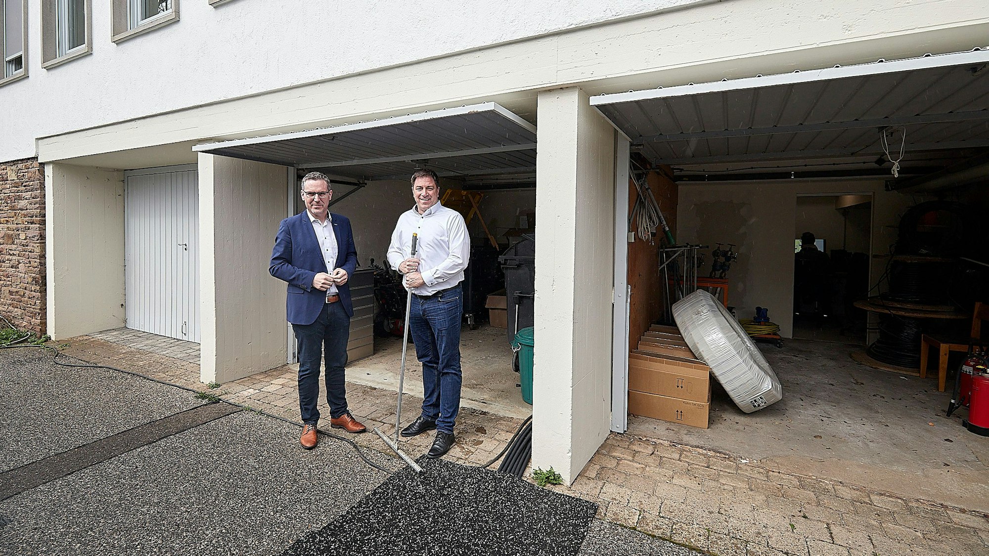 Bürgermeister Norbert Crump (l.) und Stefan Grieshaber stehen vor drei Garagen am Rathaus der Gemeinde Nettersheim in Zingsheim.