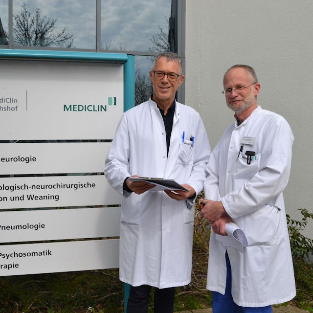 Zwei Ärzte stehen in weißen Kitteln vor dem Eingang der Mediclin-Rehaklinik in Reichshof.