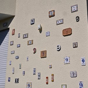 Das Foto zeigt eine Hauswand mit vielen Hausnummern.