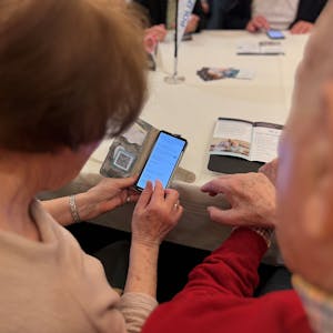 Eine Rentnerin und ein Rentner schauen gemeinsam auf ein Smartphone.