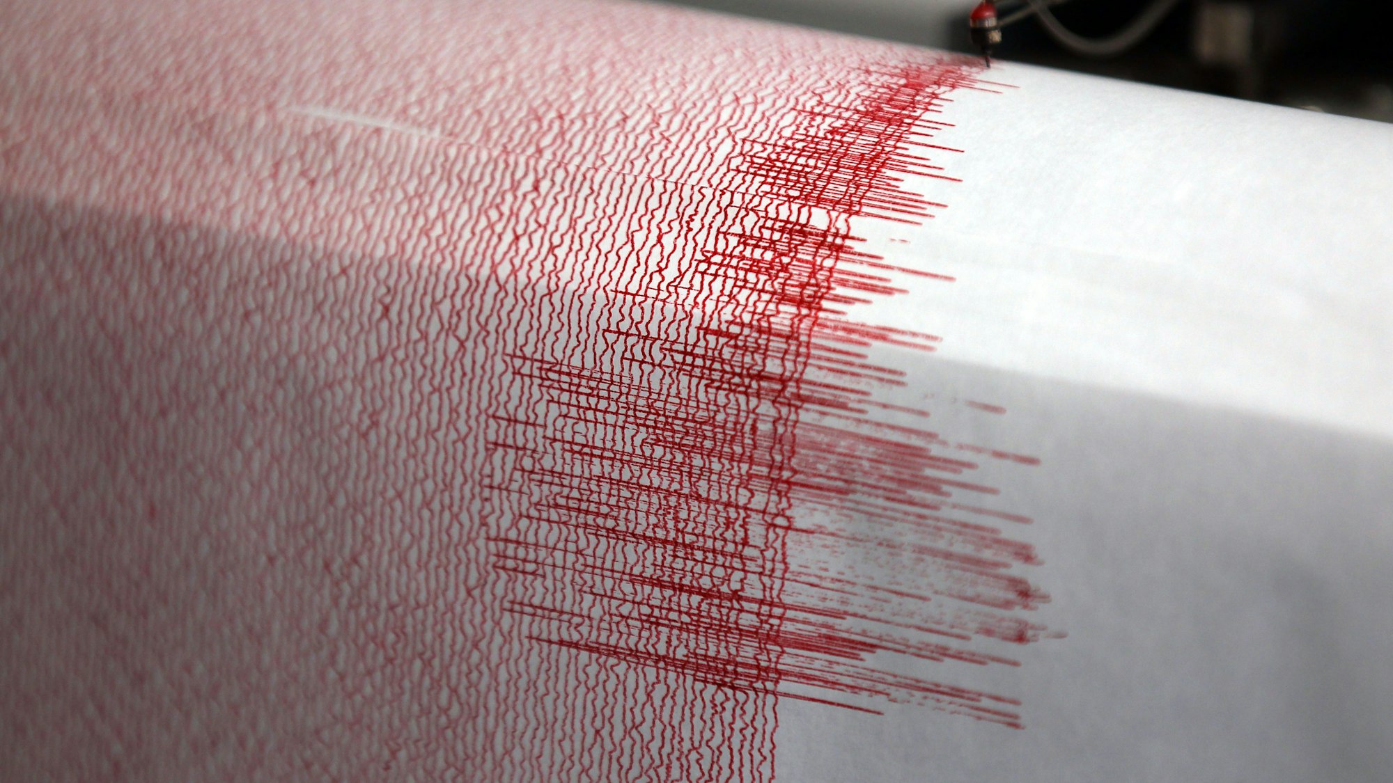 Der Seismograph einer Erdbebenwarte verzeichnet Ausschläge.Zu sehen sind sie in Form einer roten Linie auf einem Blatt Papier.
