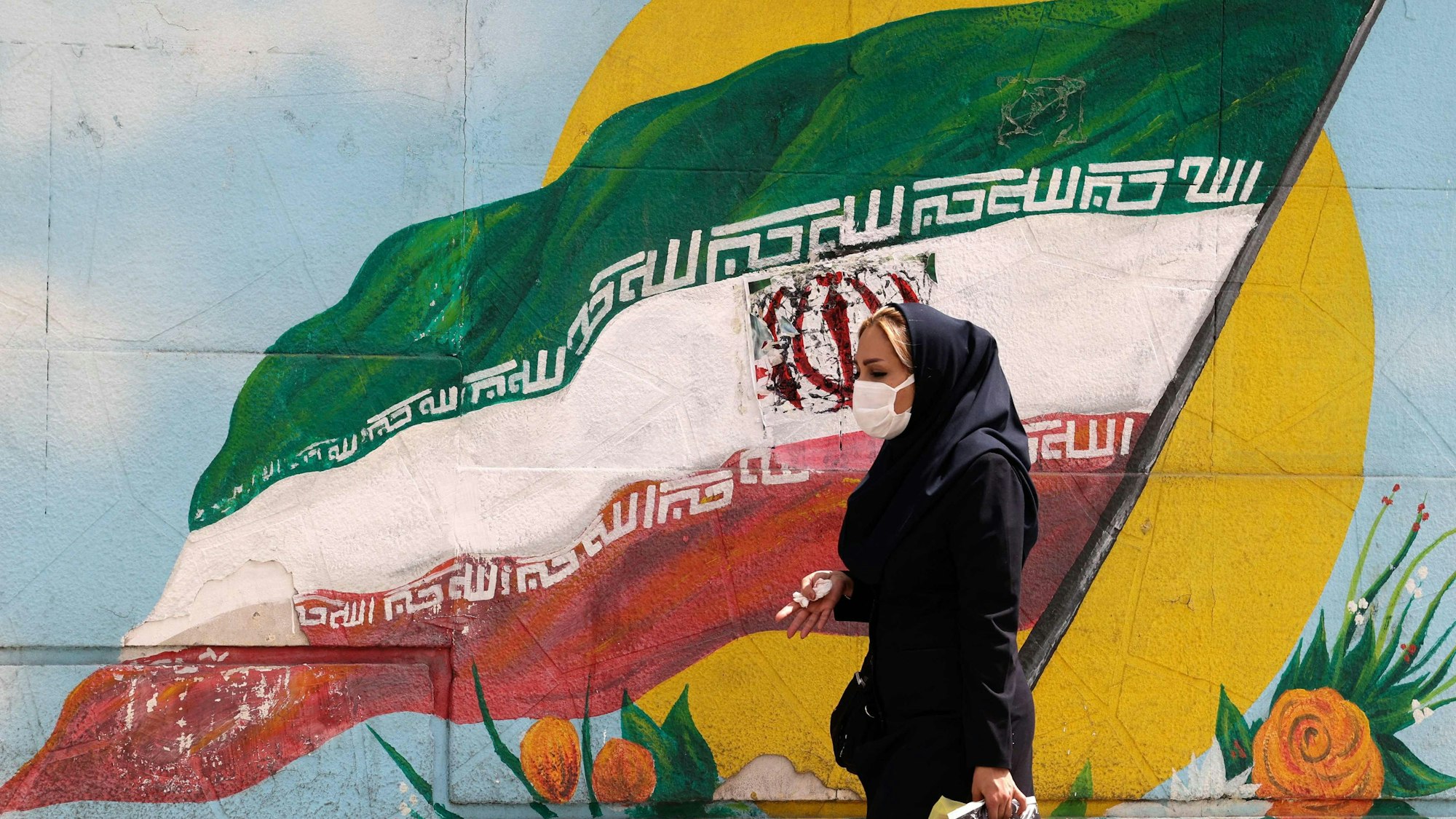 Frau läuft vor iranischer Flagge