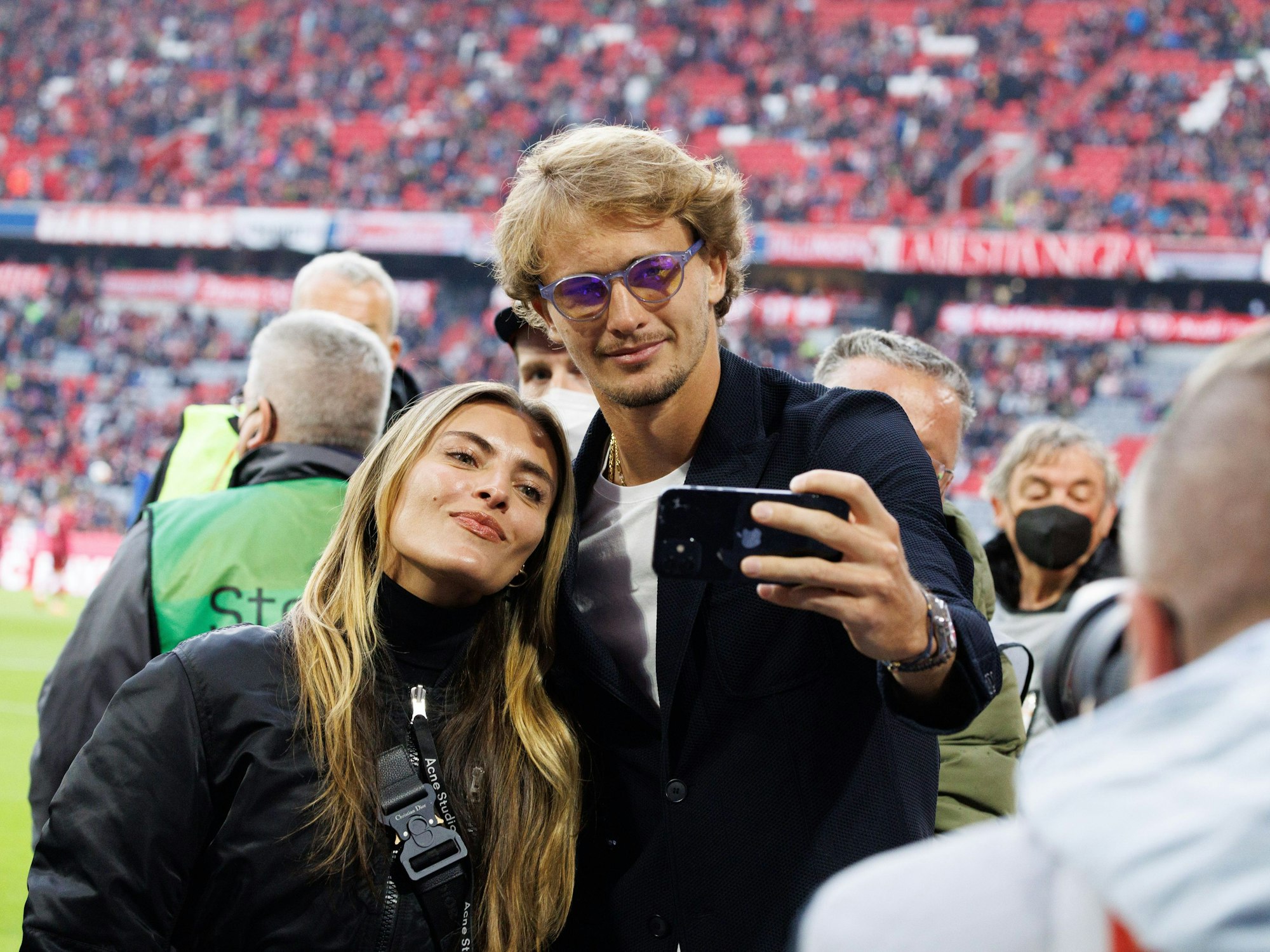 Alexander Zverev und Sophia Thomalla machen ein Selfie am Spielfeldrand in der Allianz-Arena.