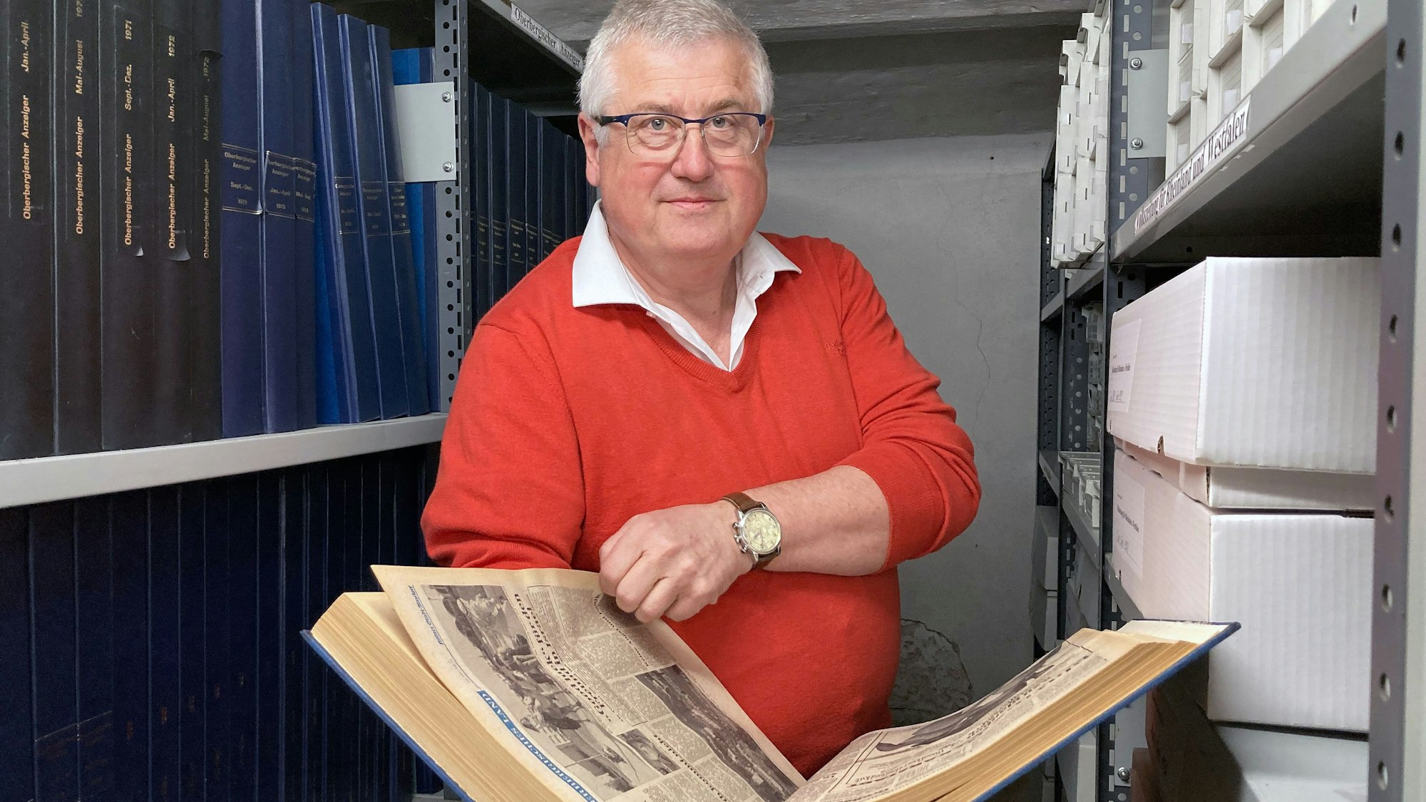 Archivar Volker Wetzler hält eine alte, aufgeschlagene Ausgabe einer Zeitung in den Händen.