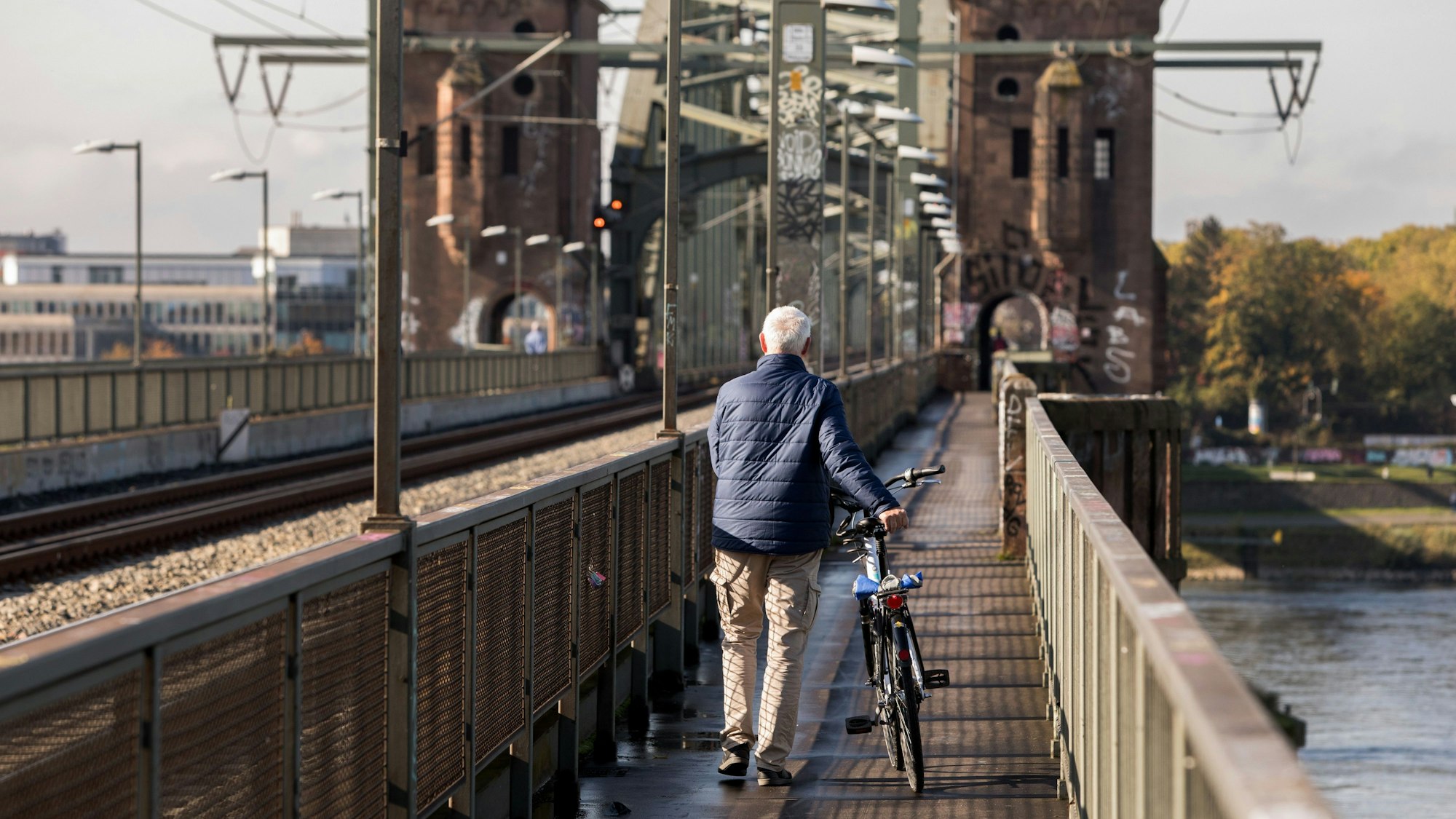 Ein Mann mit Fahrrad geht über die Südbrücke ins Rechtsrheinische.