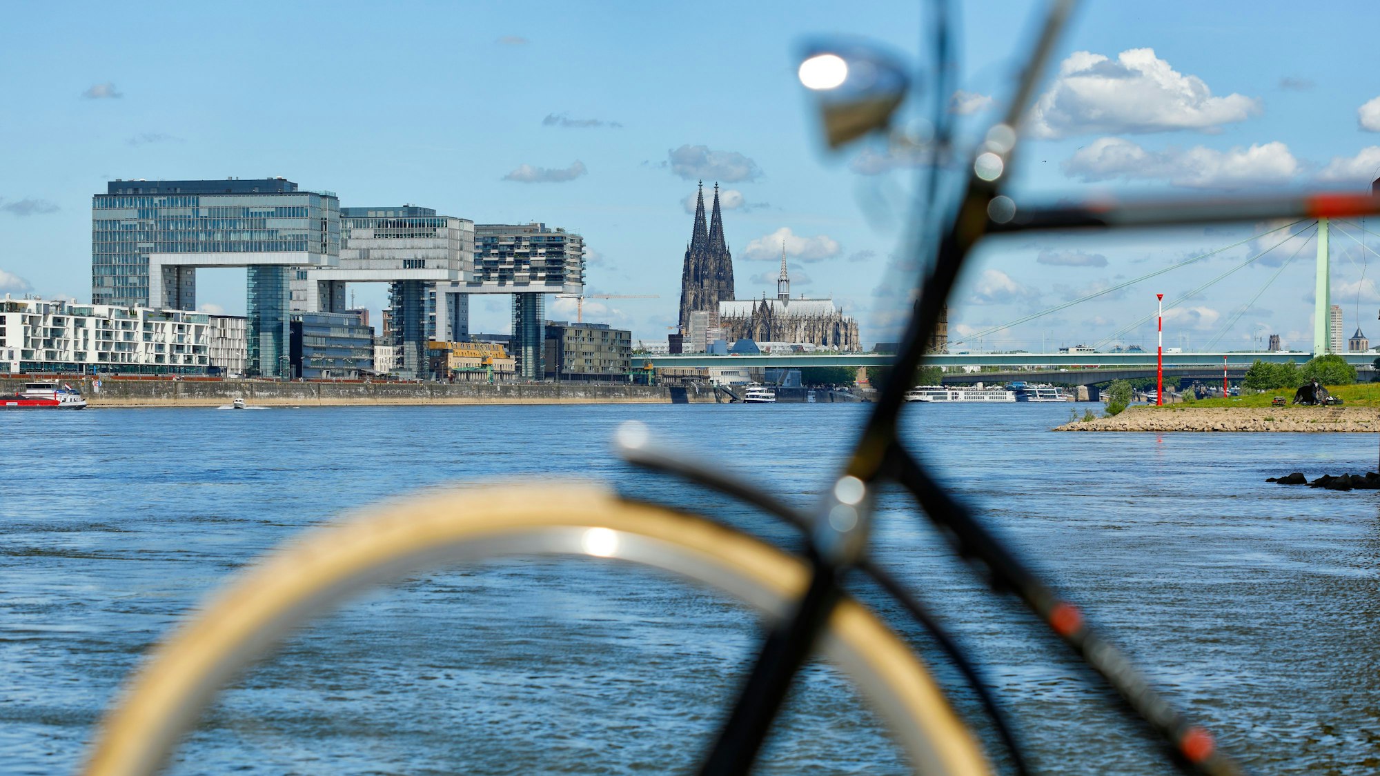 Fahrrad unscharf im Vordergrund vor Köln Kulisse mit Kranhäusern und Dom