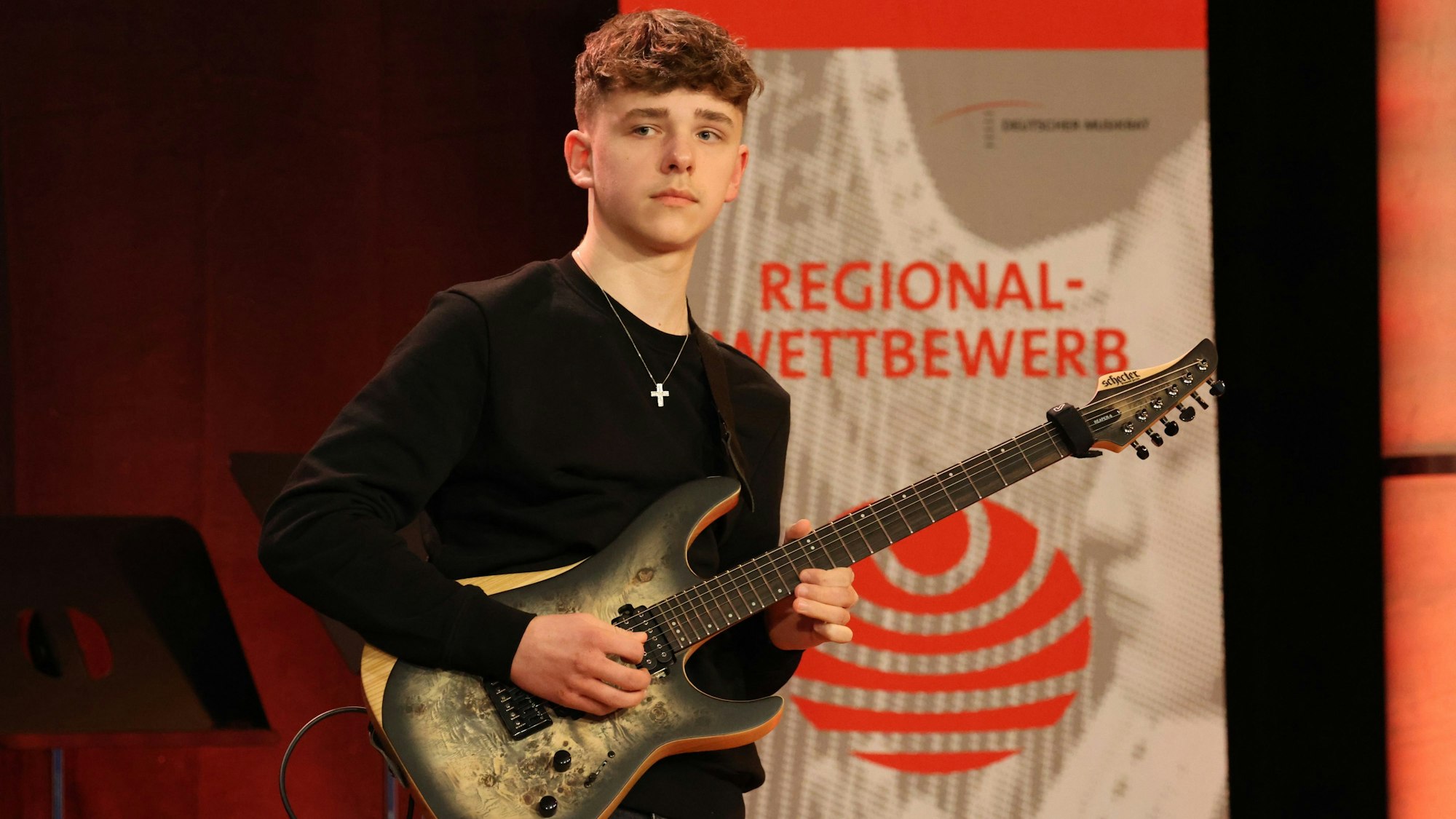 Lennart mit seiner Gitarre auf der Bühne des Regionalwettbewerbs.