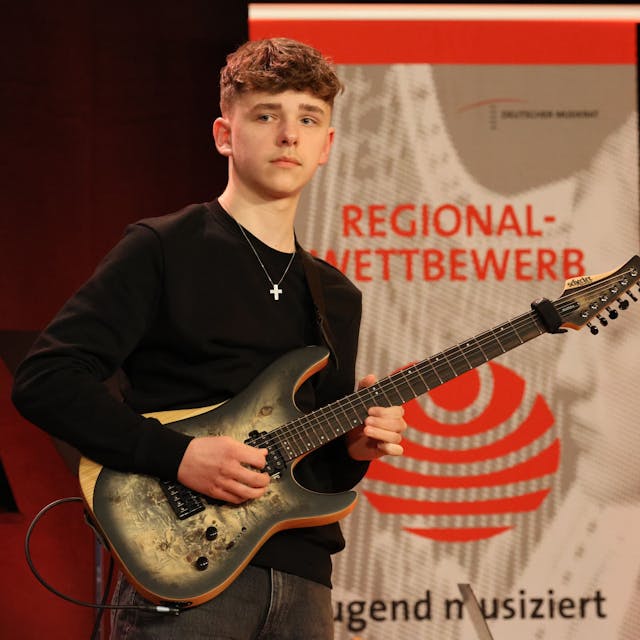 Lennart mit seiner Gitarre auf der Bühne des Regionalwettbewerbs.&nbsp;
