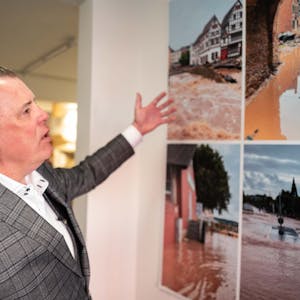 Marc Brucherseifer, Geschäftsführer des City Outlets, deutet auf einige Bilder, die nach der Flutkatastrophe in Bad Münstereifel entstanden sind.