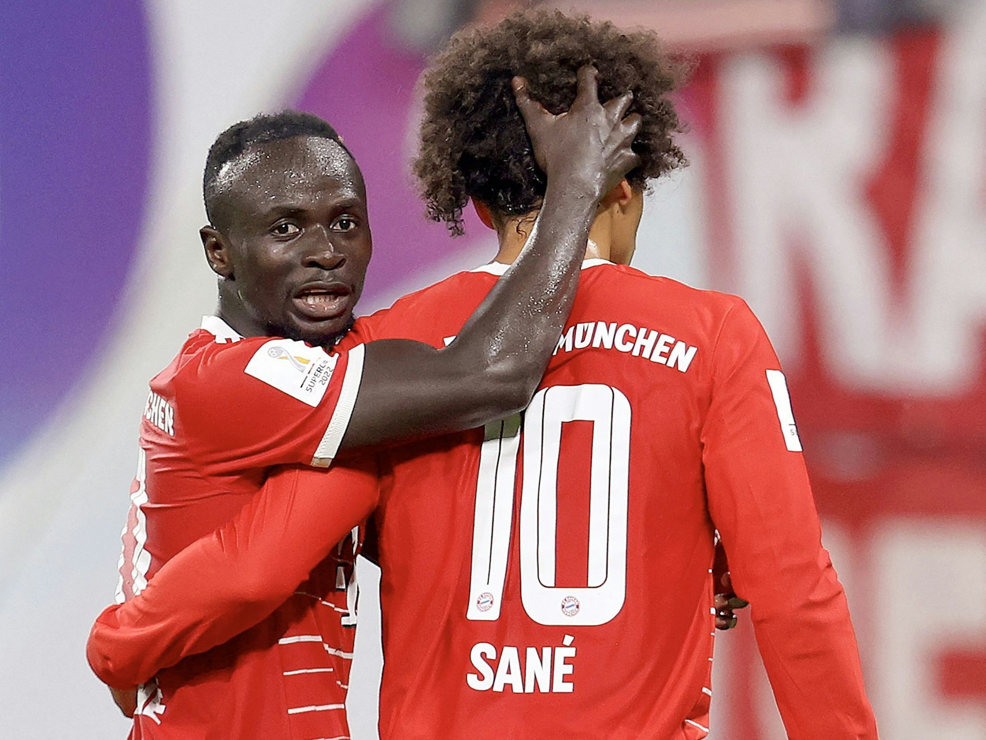 Die Bayern-Spieler Sadio Mané und Leroy Sané jubeln gemeinsam auf dem Platz.