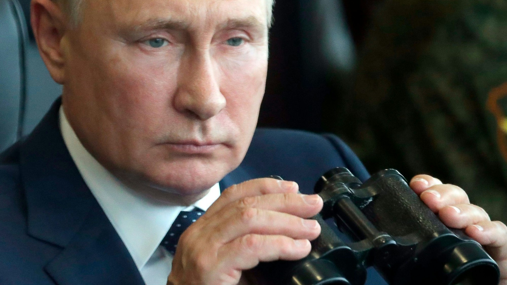 Wladimir Putin, Präsident von Russland, hält ein Fernglas in den Händen.
