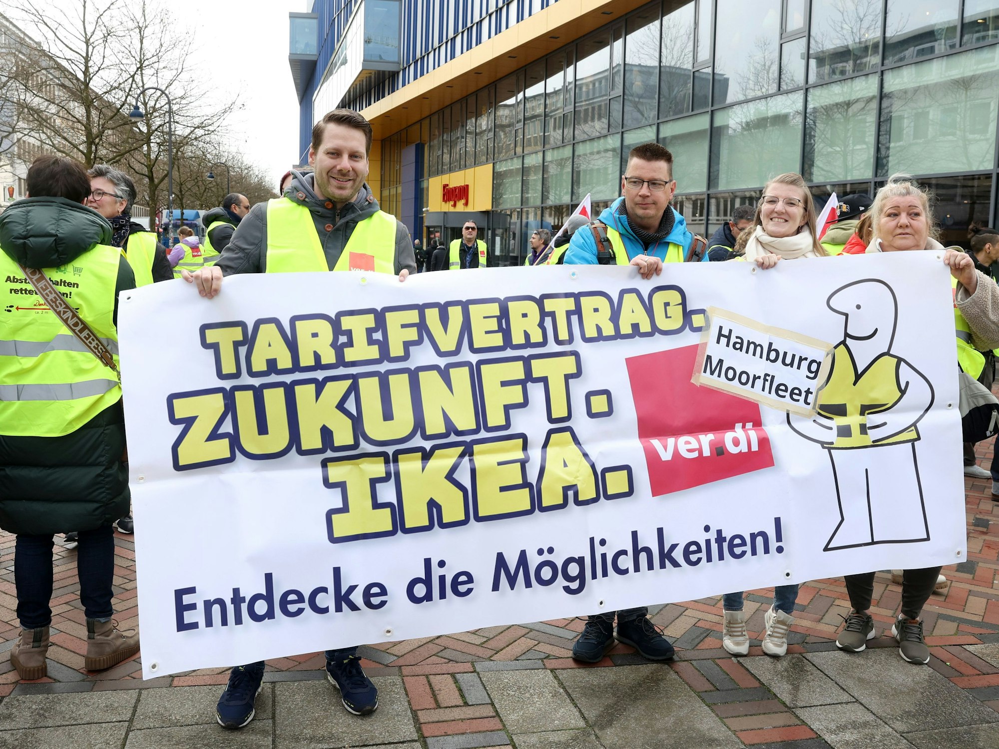 Streikende Ikea-Mitarbeiter stehen bei einer Kundgebung vor einer Ikea-Filiale in Hamburg-Altona und halten ein Transparent mit der Aufschrift „Tarifvertrag. Zukunft. Ikea. Endecke die Möglichkeiten!“