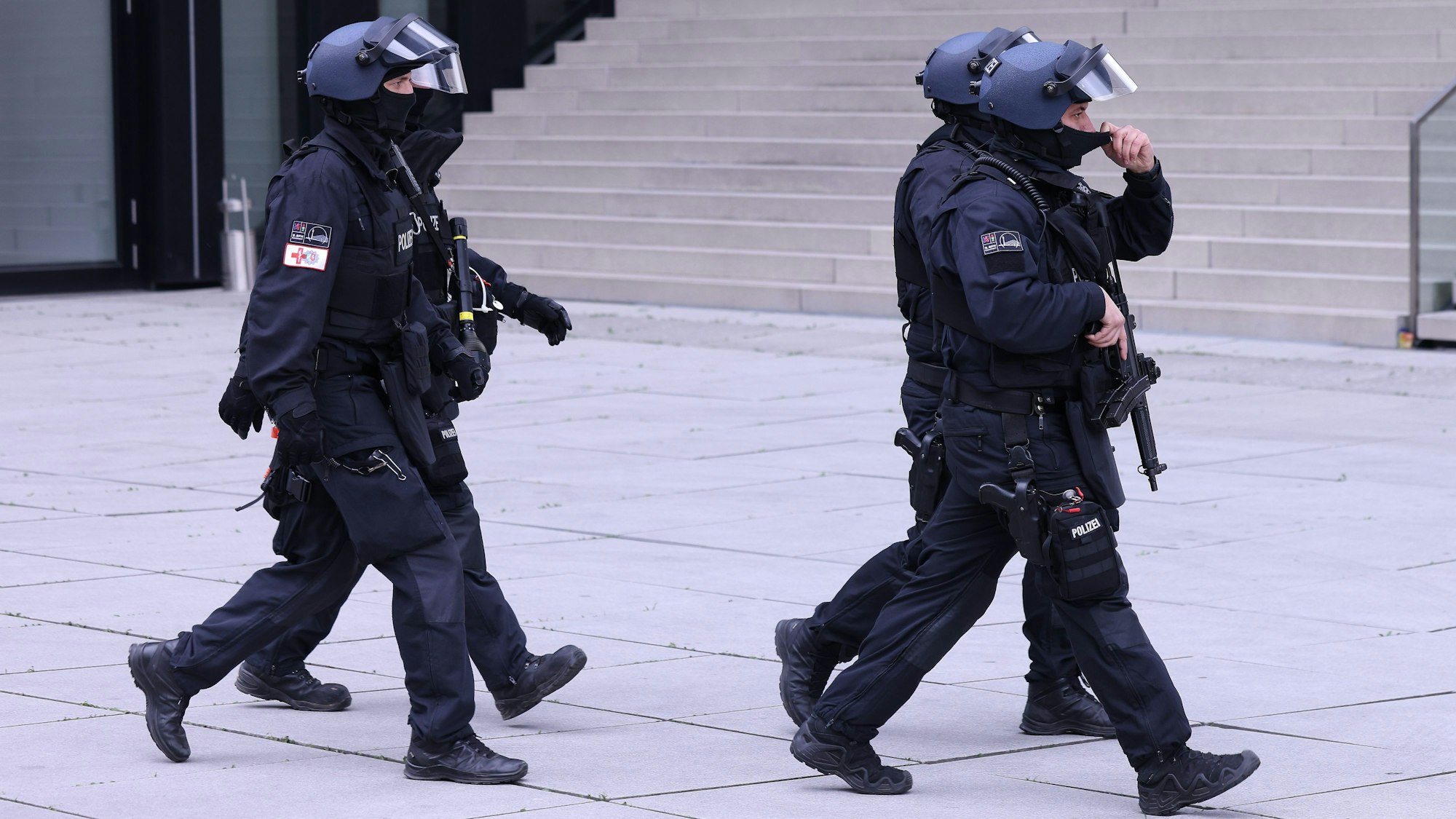 Vier Einsatzkräfte der Polizei tragen Helme und sind mit Maschinenpistolen bewaffnet.