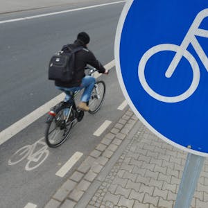 Ein Mann fährt mit seinem Fahrrad auf einem mit einem Verkehrsschild gekennzeichneten Radweg.&nbsp;