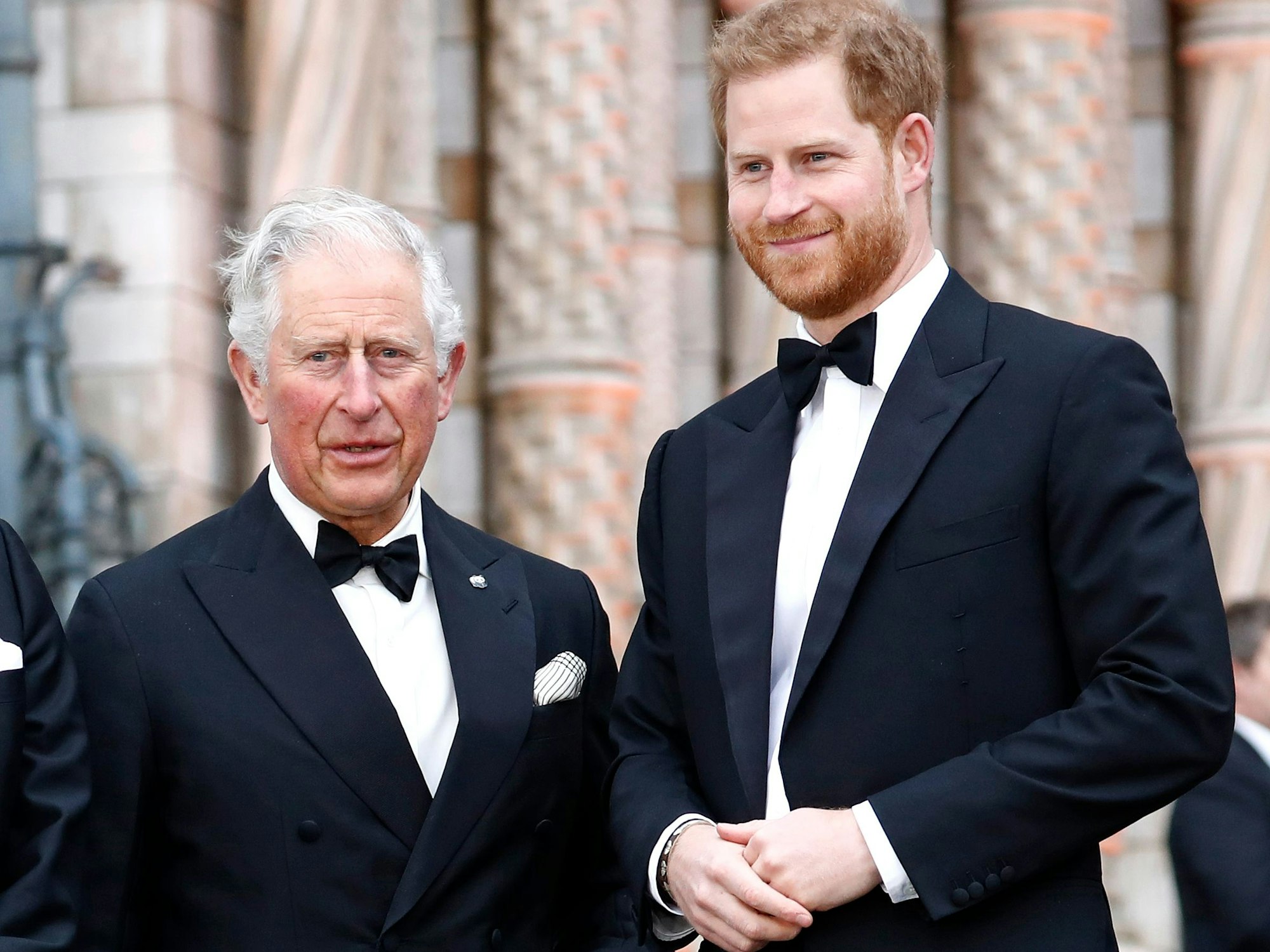 König Charles III. und Prinz Harry stehen in Abendgarderobe bei einem öffentlichen Termin nebeneinander.