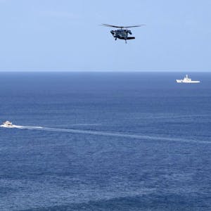 Ein Hubschrauber sucht die Gewässer vor einer Insel ab.